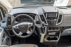 the interior of a vehicle with dashboard, steering wheel and dash board in grey color