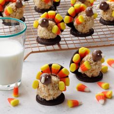 cookies decorated with candy and candy corn on a cooling rack next to a glass of milk