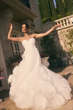 a woman in a white wedding dress posing for the camera with her arms spread out