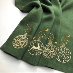 three christmas ornaments on green fabric with gold foilwork and golden thread, sitting next to each other