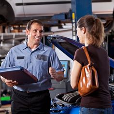 a man and woman talking to each other while standing in front of a blue car