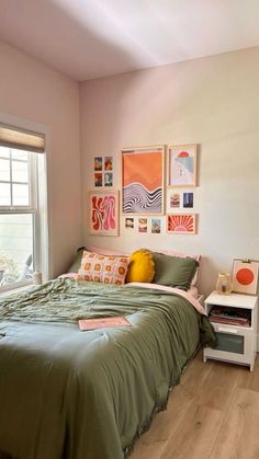 a bedroom with green bedding and pictures on the wall