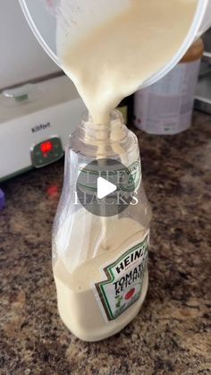 someone is pouring milk into a bottle on the counter