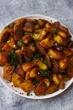 a white plate topped with potatoes covered in parsley