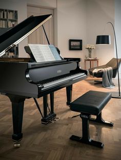 a grand piano sitting in a living room next to a chair and ottoman on a hard wood floor