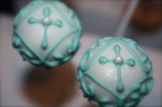 two white cake balls with green frosting and cross decorations on them, sitting on a table