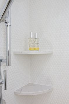 a white shelf in the corner of a shower with soap and lotion on it