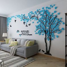 a living room with blue and black tree wall decals on the walls, along with two couches