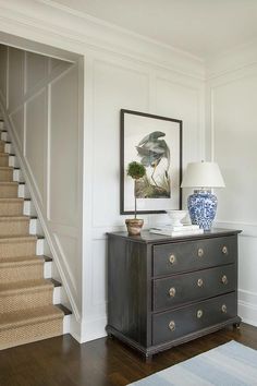 a blue and white vase sitting on top of a dresser next to a stair case