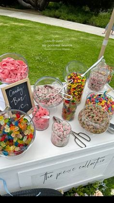 a table topped with lots of candy and candies on top of a grass covered field