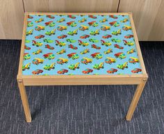 a child's wooden table with colorful cars on it