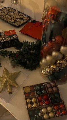 a table topped with lots of christmas decorations next to a vase filled with balls and ornaments