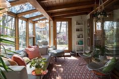 a living room filled with lots of furniture and windows covered in wood planked ceilings