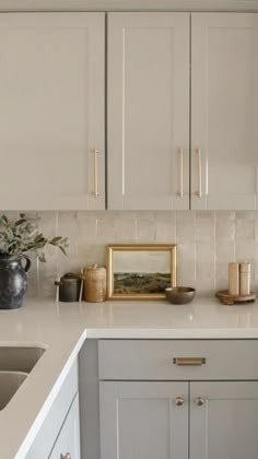 a kitchen with white counter tops and gold trim on the cabinet doors is seen in this image