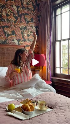 a woman sitting on top of a bed in a bedroom next to a tray of food