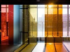 the sun shines brightly through windows in an office building's lobby, which has multiple colored glass walls