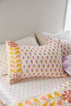 a bed topped with lots of pillows next to a pillow on top of a wooden floor