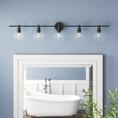 a bath tub sitting under a bathroom mirror next to a potted plant and sink