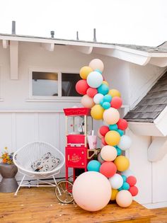 the balloon arch is decorated with multicolored balloons and stands in front of a white house