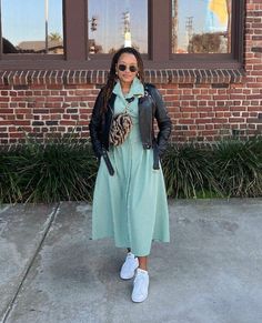 a woman standing in front of a brick building wearing sunglasses and a dress with a heart on it