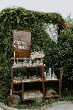 an old fashioned cart with liquor bottles and glasses on it in front of a sign