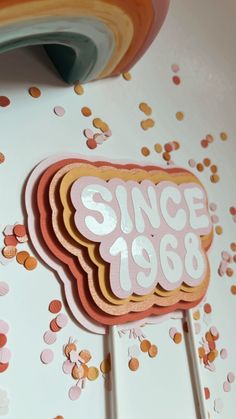 a cake topper with the word since 80's on it sitting next to confetti sprinkles