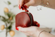 a woman is holding a small red purse in her hand while another person holds it