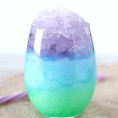 a glass filled with ice sitting on top of a table next to a pink and blue straw