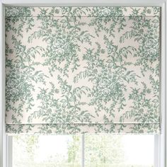 a window with a green and white floral roman blind in front of the windowsill