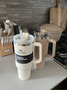 a coffee cup sitting on top of a counter next to a blender and utensils