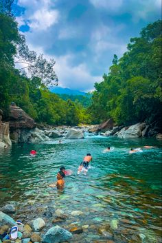 people swimming in a river surrounded by rocks