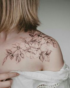 a woman's shoulder with flowers and leaves on the back of her body,