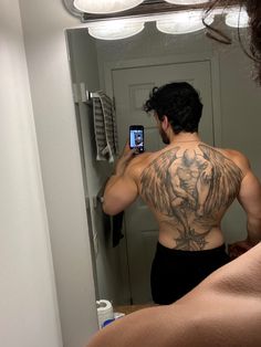 a man taking a selfie in front of a mirror with his back turned to the camera