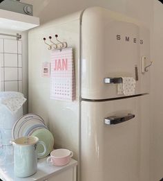 a white refrigerator freezer sitting on top of a counter next to a cup and saucer