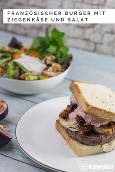 a white plate topped with a sandwich next to a bowl of salad