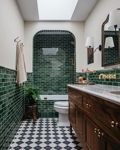 a bathroom with green tiles on the walls and black and white checkered flooring