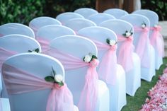 rows of white chairs with pink sashes and flowers