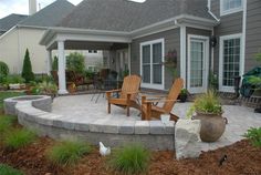 a patio with chairs and plants in front of a house