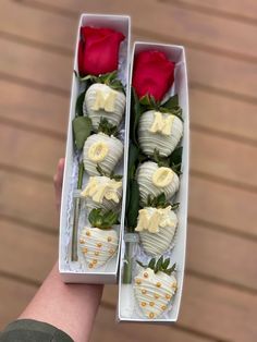 two white chocolate covered strawberries and one red rose in a box with gold trim