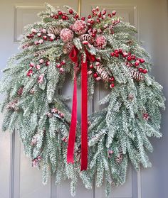 a christmas wreath with red berries and pine cones hanging on the front door to give it a festive feel