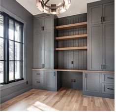 an empty room with wooden floors and gray cabinets, along with a chandelier hanging from the ceiling