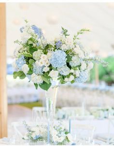 a vase filled with blue and white flowers on top of a table covered in glasses