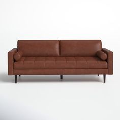 a brown leather couch sitting on top of a white floor