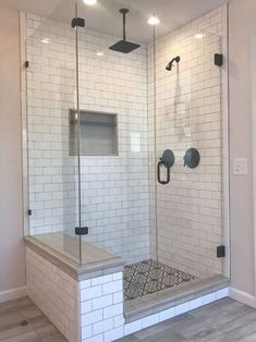 a walk in shower sitting next to a white tiled wall and wooden floored floor