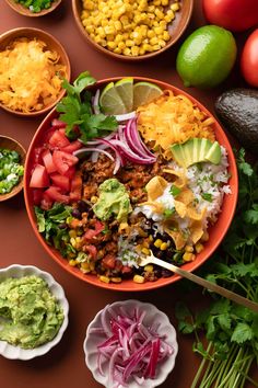 a bowl filled with lots of different types of food next to bowls of vegetables and guacamole