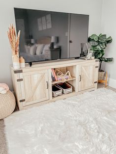 a living room with a large flat screen tv on top of a wooden entertainment center