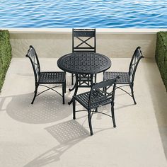 an outdoor table and chairs on a patio next to the water