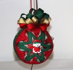 a red ornament hanging from a string with gold bows and a teddy bear on it