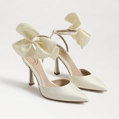 a pair of white high heeled shoes with bows