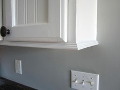 an electrical outlet on the wall next to a white cabinet with two knobs and one light switch